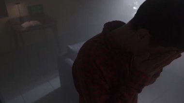 Karanlık odada elleri başının üstünde, dizüstü bilgisayarı akşam lambasıyla duran çaresiz bir adam. Bitkinlik, iş sorunları ve zihinsel sağlık stresi kavramı.