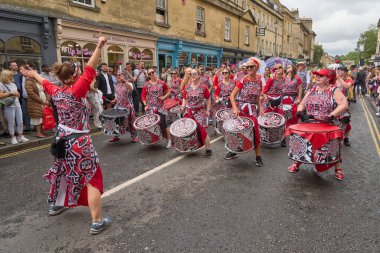 Bath, İngiltere, Birleşik Krallık - 8 Temmuz 2023: Somerset 'teki tarihi Bath kentinin caddelerinde ilerleyen geleneksel karnavalda süslü kostümlerle müzik ve dans grubu geçit töreni.