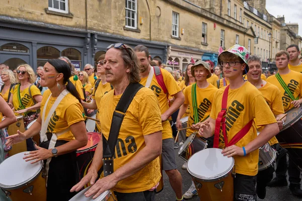 イギリス イングランド 2023年7月8日 サマセットのバスの歴史的な街を進むにつれて 毎年恒例のカーニバルで行われる華やかな衣装で音楽とダンスのグループパレード — ストック写真