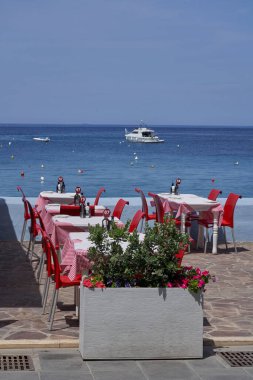 Marsalforn, Gozo, Malta - June 9, 2023: Restaurant tables and chairs set up on the sea front of Marsalforn on the coast of Gozo in Malta