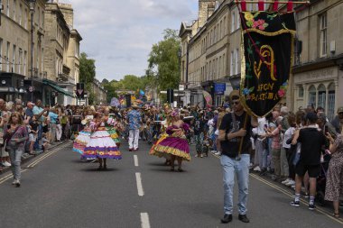 Bath, İngiltere, Birleşik Krallık - 13 Temmuz 2024: Somerset 'teki tarihi Bath kentinin caddelerinde ilerleyen geleneksel karnavalda süslü kostümlü dansçılar.