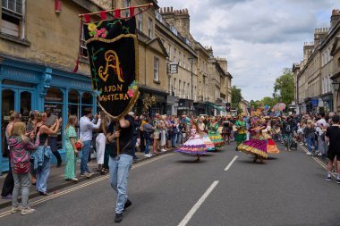 Bath, İngiltere, Birleşik Krallık - 13 Temmuz 2024: Somerset 'teki tarihi Bath kentinin caddelerinde ilerleyen geleneksel karnavalda süslü kostümlü dansçılar.