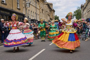 Bath, İngiltere, Birleşik Krallık - 13 Temmuz 2024: Somerset 'teki tarihi Bath kentinin caddelerinde ilerleyen geleneksel karnavalda süslü kostümlü dansçılar.