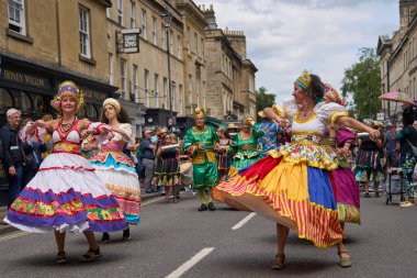 Bath, İngiltere, Birleşik Krallık - 13 Temmuz 2024: Somerset 'teki tarihi Bath kentinin caddelerinde ilerleyen geleneksel karnavalda süslü kostümlü dansçılar.