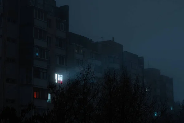 ロシアの発電所の閉鎖後キエフの住宅街の停電時に霧のアパートの複数階建ての建物内の1つのウィンドウ内の光 — ストック写真
