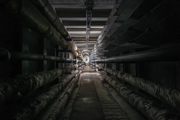 Underground concrete utility tunnel with pipes and wires. Freeze light in the tunnel.