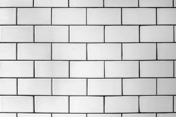 stock image The textured wall is lined offset with white glossy ceramic tiles.