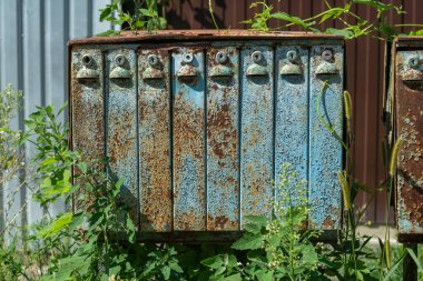 Eski, terk edilmiş, paslı, köhne, soluk mavi posta kutusu. Sokakta bir sürü kompartıman var..