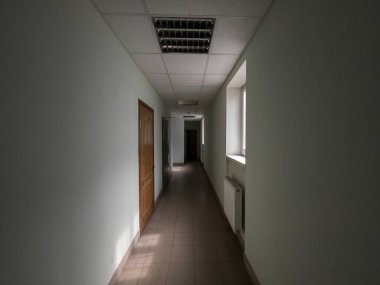 Boş karanlık ofis koridoru pencerelerle aydınlatıldı.