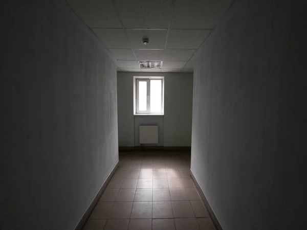 最后有窗户的空荡荡的黑暗办公室走廊 — 图库照片