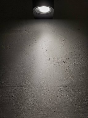 Karanlık bir odada beyaz bir duvarda spot ışığı.