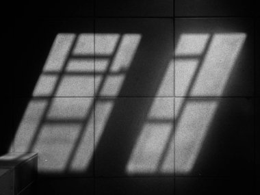 Karanlık bir odada, parmaklıklı pencerelerin gölgesi..