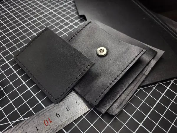 Details for making a black leather wallet on a cutting mat with a metal ruler nearby.