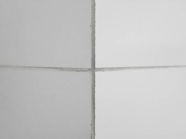 The corner of the wall is lined with white glossy ceramic tiles with gray grout between the tiles. clipart