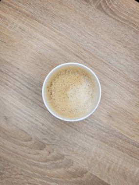 Kahvehanedeki ahşap bir masada köpüklü, tek kullanımlık beyaz bir İrlanda kahve fincanı..