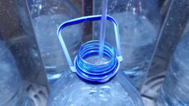 İçme suyu kutusunun içinde, su 6 litrelik plastik bir mavi şişeye dökülüyor. Şişenin boynuna yakın çekim..
