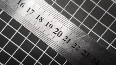 Metal bir cetvelde rakamlar değişir, çaprazlama biçer ve kesme paspasındaki ızgaranın arka planına göre rakamları hızla değiştirir. Hareketi durdur.