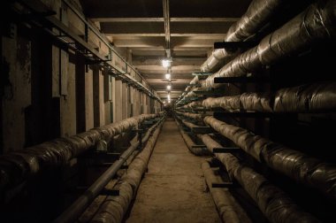 Boruları ve kabloları olan yeraltı beton kullanım tüneli.