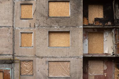 Kyiv, Ukrayna - 18 Şubat 2024: Rus ordusu tarafından bombalanan ve sonradan kontrplakla kaplanan konut binasının pencereleri.