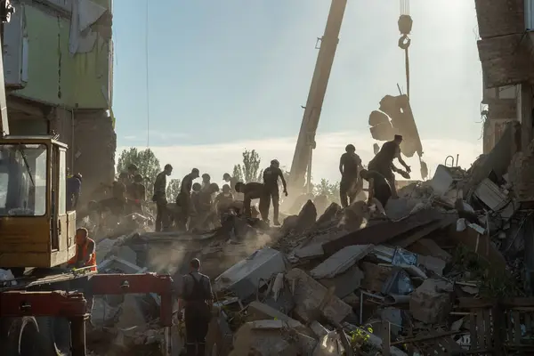 stock image KYIV, UKRAINE - JULY 8, 2024: Emergency Service workers disassembles pile of debris after a Russian missile hit a residential building in one of the residential districts of Kyiv.