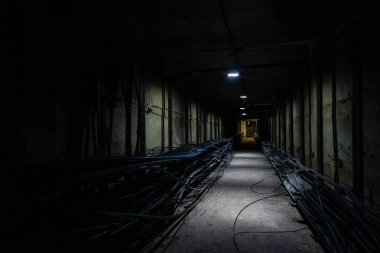 Ön planda kablo bağlantısı olan karanlık yeraltı kablo tüneli. İnternet, televizyon ve telefon için optik kabloları olan yeraltı tüneli.