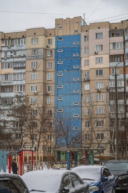Eski prefabrik dokuz katlı apartman dairesi mavi girişli, bej bej seramik kiremitlerle kaplıydı. Kyiv, Ukrayna - 15 Şubat 2025.