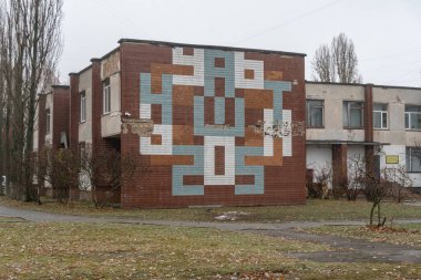 1970 'lerden kalma bir okulun ön cephesinde seramik parlak fayanslardan yapılmış eski mozaik süpergrafik. Mozaik terk edilmiş görünüyor. Obolon, Kyiv, Ukrayna - 30 Kasım 2024.