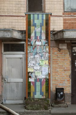 Prefabrik bir apartmanın girişindeki seramik fayans paneli, kısmen reklamlarla kaplı. 1980 'lerin başında yaratılmış. Kalynivka, Brovary bölgesi, Kyiv bölgesi, Ukrayna - 8 Mart 2025.
