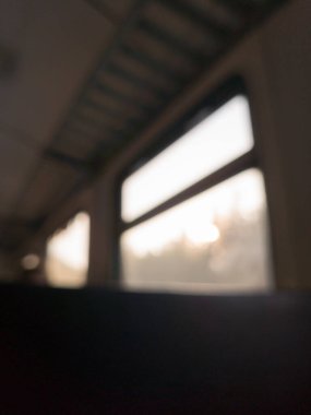 Trenin içini bulanık bir şekilde görebiliyoruz. Penceresi yumuşak güneş ışığını ve dışarıdaki soyut manzarayı gösteriyor..