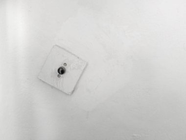 Beyaz duvar arkaplanı boyalı, eğik elektrik düğmesi var. Boşluğu sağ tarafa kopyala.