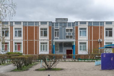 İki katlı, turuncu, beyaz ve gri kaplamalı prefabrik bir anaokulunun ön girişi. Troieshchyna İlçesi, Kyiv, Ukrayna 6 Nisan 2025.
