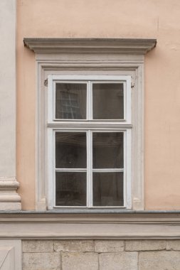 Bej kaplama duvarında klasik çerçeve olan eski beyaz ahşap pencere. Pencerede dört kuşak ve yıpranmış boya var..