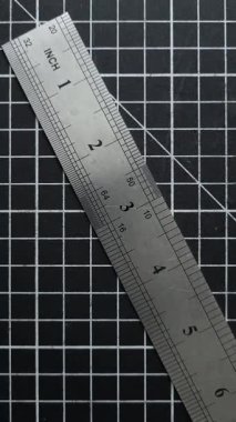 Metal cetvel, üzerinde inç ve milimetre işaretleri olan siyah şebeke kesme paspası..