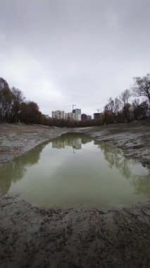 Boş göl, durgun su ve bulutlu gökyüzünün altındaki konut binaları..