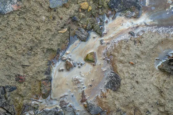 Kirli topraklarda gökkuşağı parıltısıyla yağlı film kayalar ve suyla.