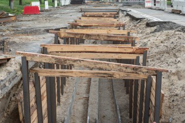 Şehir caddesindeki bir yeraltı altyapı tesisi için ahşap ve metal destekli siper inşaatı.