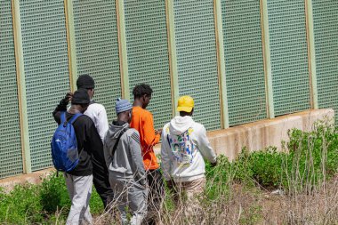 Tenerife, Kanarya Adaları, İspanya - 30 Mart 2024: Tenerife 'de bir çitin yanında yürüyen yasadışı Sahra altı göçmenleri