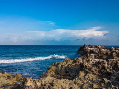 Cancun, Playa Gaviota 'nın kayalık kıyılarında çarpıcı bir gün batımı. Karayip dalgaları yavaşça kıyıya vuruyor.