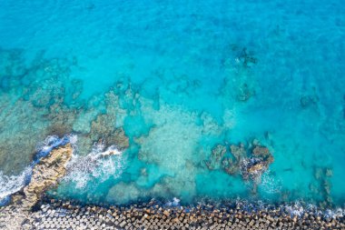 Cancun, Playa Gaviota 'nın kristal berrak sularında kübik bloklardan oluşan geometrik bir dalgakıran. Yapı, dingin ve resmedilmiş kıyı manzarasını aydınlatan canlı mavi denizle güzel bir tezat oluşturuyor.