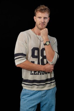 Şık ve kendine güvenen bir adam spor bir kazak ve klasik bir kot pantolon giyer. Günlük rahatlığı atletik kenarla birleştirir.