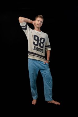 Şık ve kendine güvenen bir adam spor bir kazak ve klasik bir kot pantolon giyer. Günlük rahatlığı atletik kenarla birleştirir.