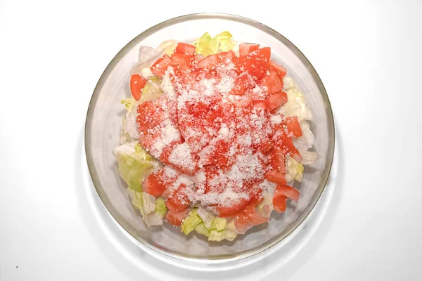 Glass bowl with fresh iceberg lettuce, tomatoes and grated cheese. Restaurant dish. Vegetable salad. Glass bowl. Salad with iceberg, tomatoes and grated cheese. Healthy food. Dietary nutrition.