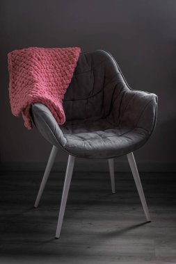 Evin içinde bir sandalyenin üzerinde lüks bir battaniye. Yumuşak battaniye. Sandalyenin üzerine örülmüş bir battaniye. İç mekan. Ev rahatlığı. Ev yapımı battaniye. Yumuşak iplik. Kışın sıcak olur. İç kısımda örgü ögeler var..