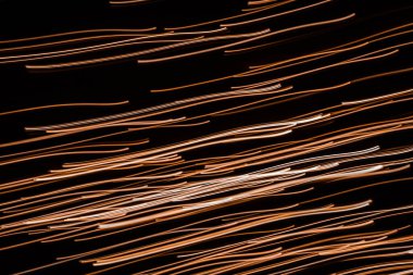 Radiant lines. Long exposure. Shiny dashes on a black background. Gold on black. Light of illumination.