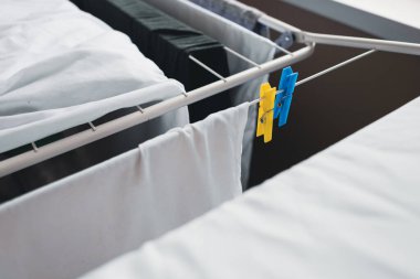 Blue and yellow clothespins. White color. Clothespins on the dryer. Things dry after washing. Fresh smell. Clean linen. To wash things. White stuff. 