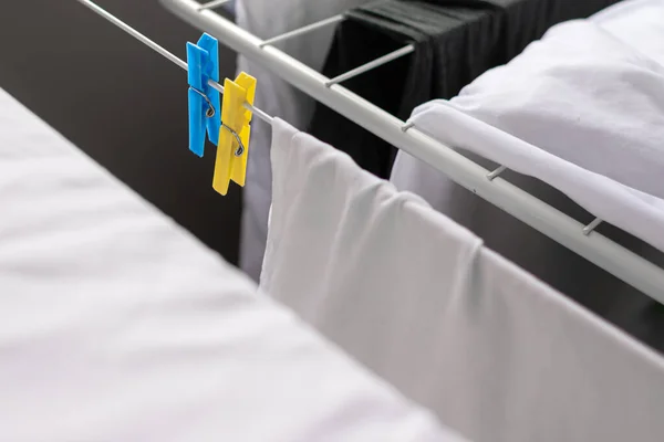 Blue and yellow clothespins. White color. Clothespins on the dryer. Things dry after washing. Fresh smell. Clean linen. To wash things. White stuff.