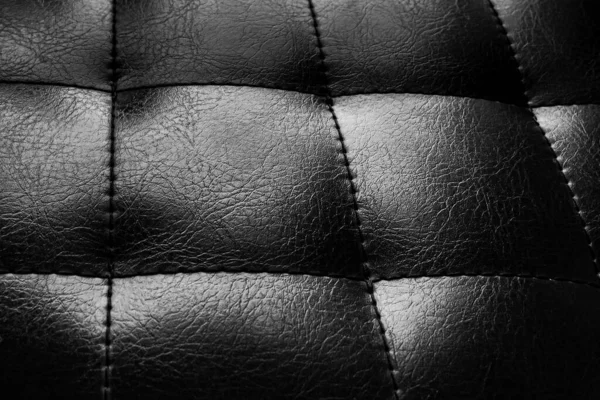 Black background made of quilted leather. Skin texture. Leather chair. Black leather background.