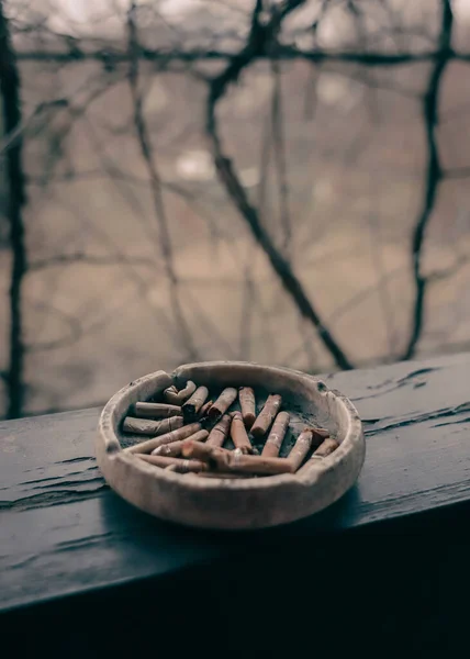 木製のテラスビームにバットを持つ粘土灰皿 路上でタバコを吸う タバコの残骸だ ニコチン中毒 タバコの吸い殻で灰皿 危険な癖だな — ストック写真