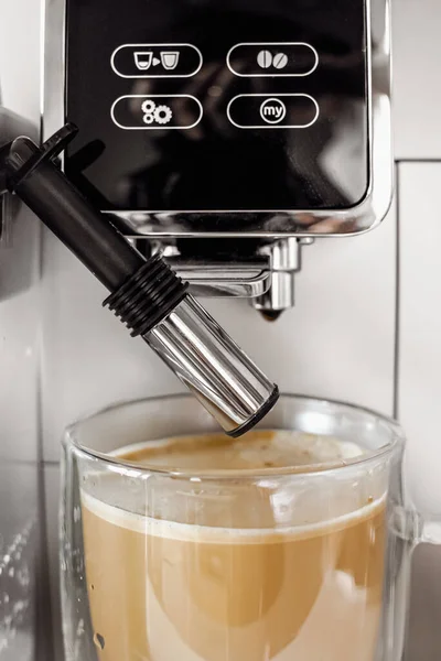 Coffee drink with milk foam in a coffee machine. Home coffee machine. Coffee with milk. Glass cup. Morning coffee. Coffee break. Barista job. Tasty warming drink.