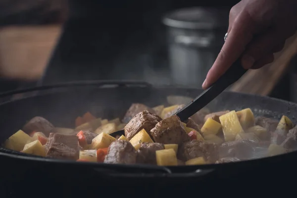 stock image A meat dish for a large company. Fried potatoes with meat. Stew on fire. Cast iron cauldron. Ukrainian cuisine. Lots of food. Barbecue party.